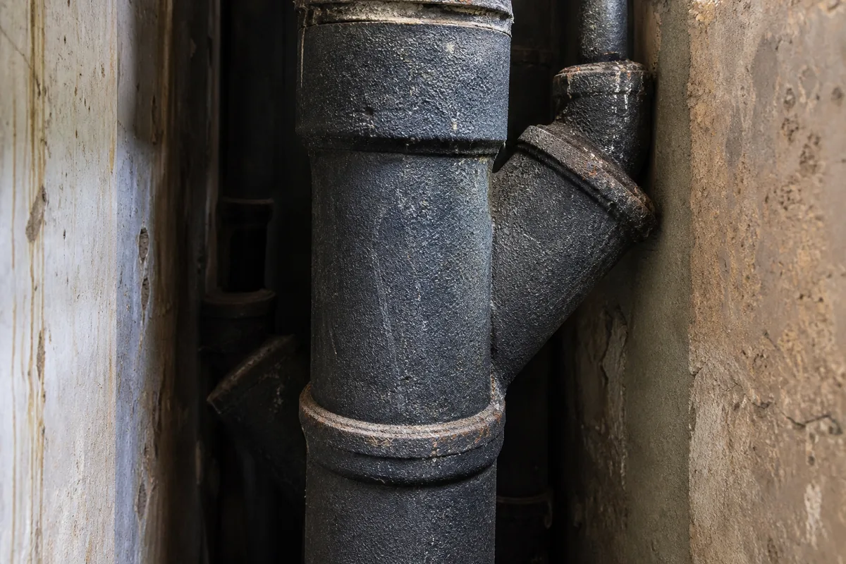 Colonne d’évacuation en fonte dans une gaine technique d’immeuble ancien